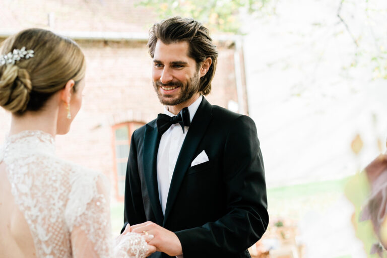 Braut und Bräutigam stehen Hand in Hand in einem ruhigen Moment vor ihrem Eheversprechen bei einer freien Trauung