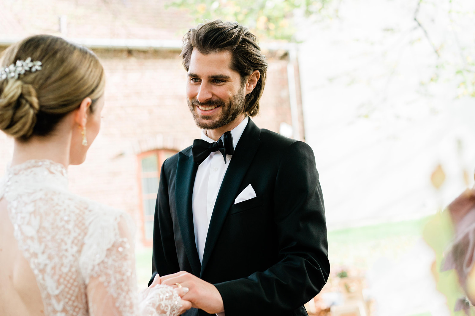 Braut und Bräutigam stehen Hand in Hand in einem ruhigen Moment vor ihrem Eheversprechen bei einer freien Trauung
