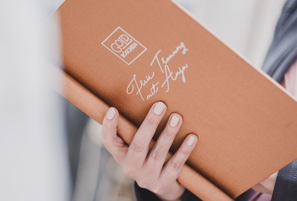 Traurede schreiben. Hand der Traurednerin Goldröschen mit Rednermappe bei einer freien Trauung