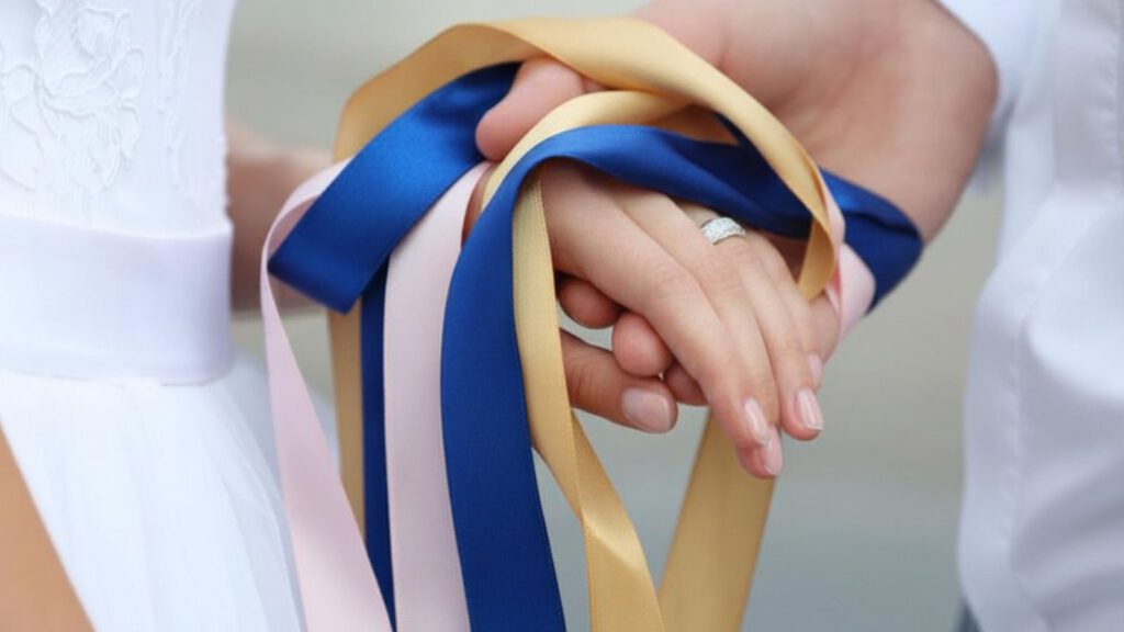 Handfasting freie Trauung Hände mit blauen und goldenen Bändern verbunden