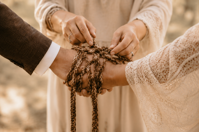 Handfasting Ritual mit geflochtenen Bändern über den Händen eines Brautpaares bei einer freien