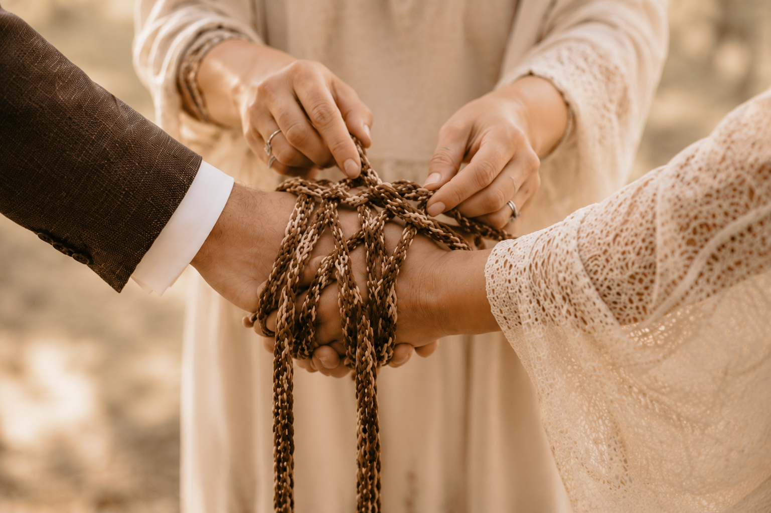 Handfasting Ritual mit geflochtenen Bändern über den Händen eines Brautpaares bei einer freien
