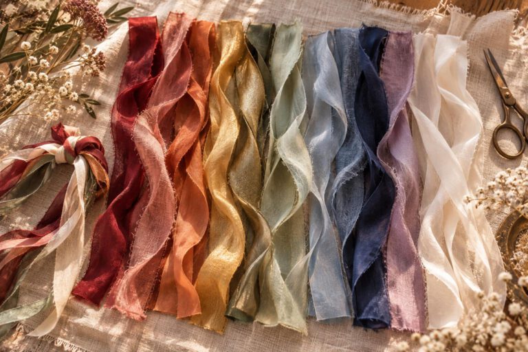 Handfasting Farben: Bänder aus Seide und Chiffon in Rot, Rosa, Orange, Gold, Grün, Salbei, Hellblau, Dunkelblau, Flieder und Creme nebeneinander auf Leinen
